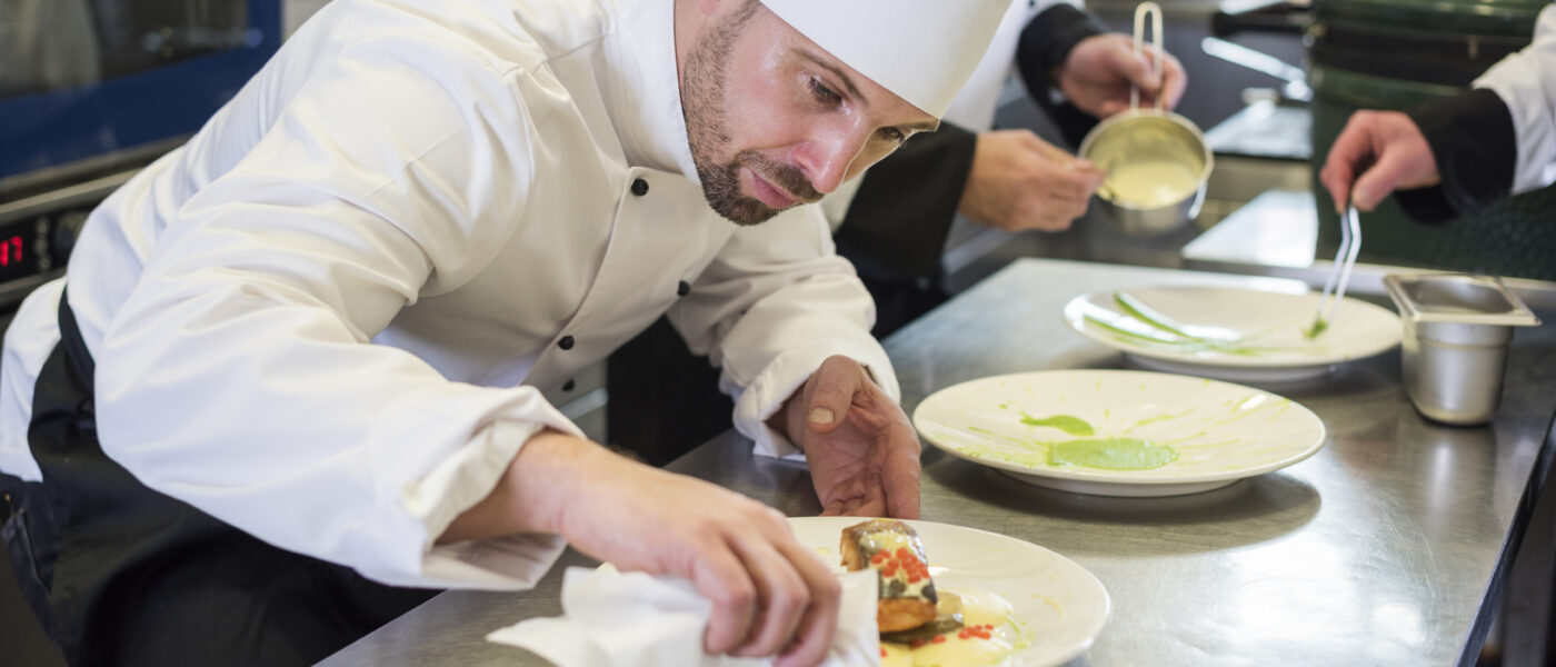 Un chef cuisinier dresse un plat dans la cuisine d'un restaurant gastronomique