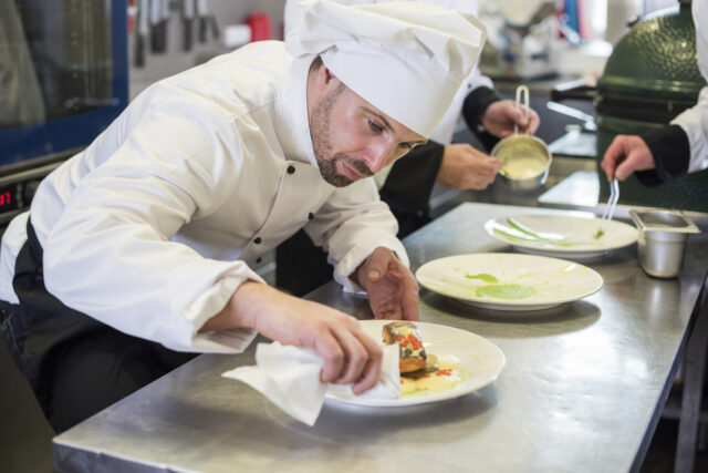 Un chef cuisinier dresse un plat dans la cuisine d'un restaurant gastronomique