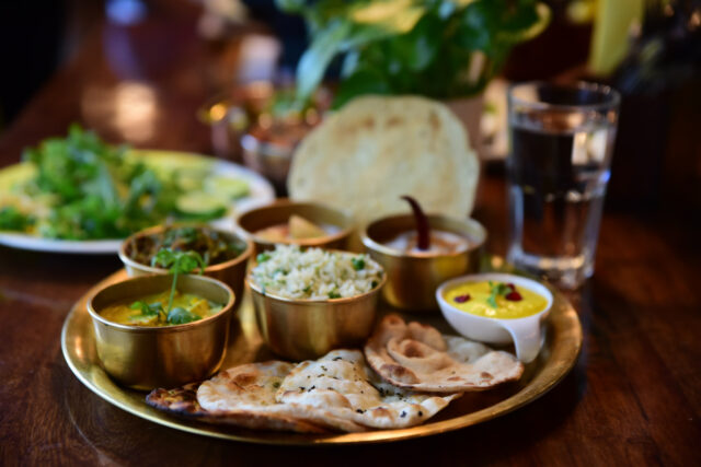 Thali végétarien traditionnel du nord de l'Inde, avec riz, pains et currys, servi sur une table en bois