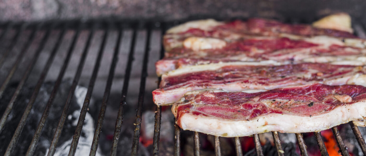 Morceaux de viande fumés disposés sur des braises dans un fumoir à barbecue
