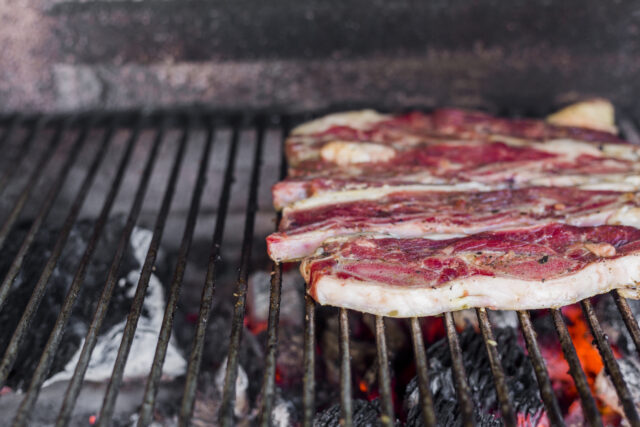 Morceaux de viande fumés disposés sur des braises dans un fumoir à barbecue